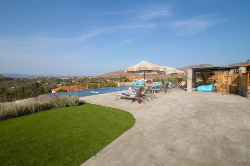 a patio with a pool and chairs and an umbrella at Lampetos Houses Molyvos in Mithymna