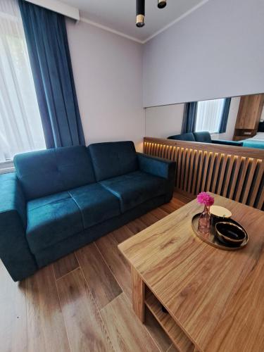 a living room with a blue couch and a coffee table at Apartament SZAFIR in Zastań