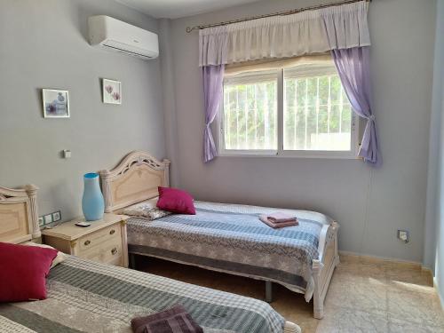 a bedroom with two beds and a window with purple curtains at Villa Casa Kenaz in El Campello