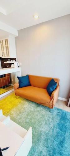an orange couch with blue pillows in a living room at Cosy SeaView, High Floor, free Netflix in Bangsaen