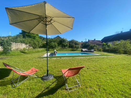 two chairs and an umbrella next to a pool at Chez Odette chambre Erable et Glycine in Esnoms-au-Val