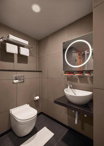 a bathroom with a toilet and a sink and a mirror at Ginger Ahmedabad Vastrapur in Ahmedabad