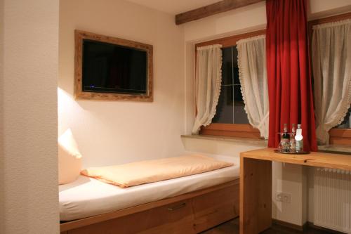 a small room with a bed and two windows at Hotel Alpensonne in Riezlern