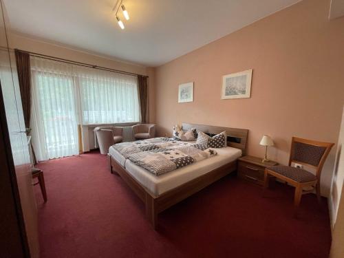 a bedroom with a bed and a chair in it at Hotel Zur Mosel in Minheim