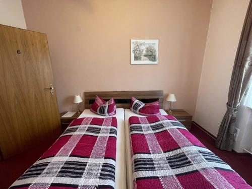 two beds in a hotel room with plaid sheets at Hotel Zur Mosel in Minheim