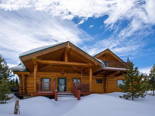 a log cabin in the snow with a blue sky at Miles Behind Log Cabin in Fraser