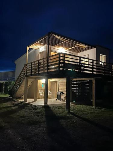 a large house with a deck at night at Maison Chalet 200 m de la plage climatisation et Wifi in Gruissan