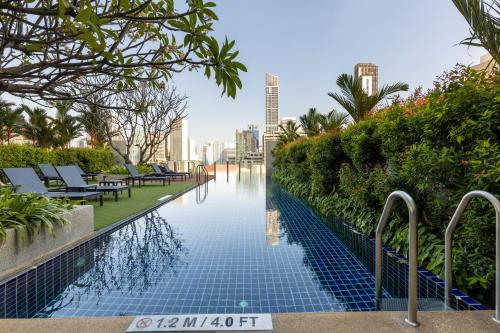 a swimming pool with chaise lounges and palm trees at Aloft by Marriott Bangkok Sukhumvit 11 in Bangkok