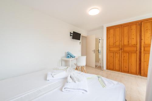 a bedroom with a white bed and a wooden cabinet at Villa Enderrossall in Porto Cristo