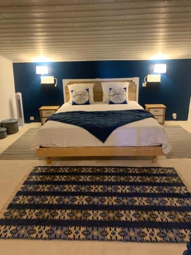 une chambre avec un grand lit avec un mur bleu dans l'établissement Maison des lavandes, à Villars