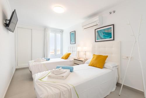a white room with two beds and a tv at Villa Enderrossall in Porto Cristo