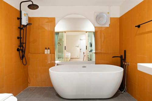 a white tub in a bathroom with orange walls at Horange Phuket Town in Phuket Town