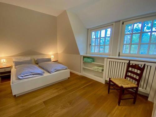 a bedroom with a bed and a desk and two windows at Haus-Seemoewe in Süddorf