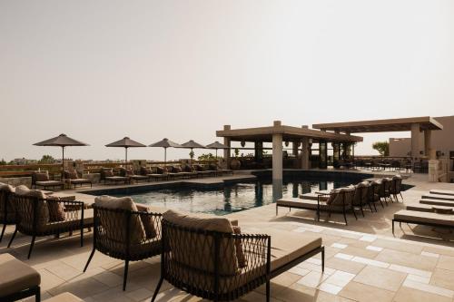 a swimming pool with chairs and tables and umbrellas at Momi Slow Living Hotel in Hersonissos