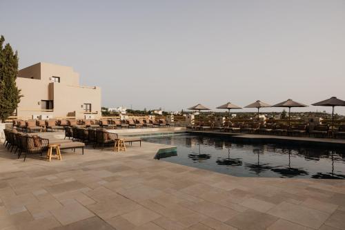 a pool with tables and chairs and umbrellas at Momi Slow Living Hotel in Hersonissos