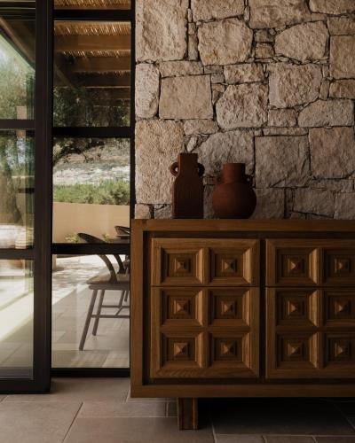 a wooden cabinet with two vases on it in front of a stone wall at Momi Slow Living Hotel in Hersonissos