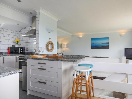 a kitchen with white cabinets and blue stools at Mor Glas in Abersoch
