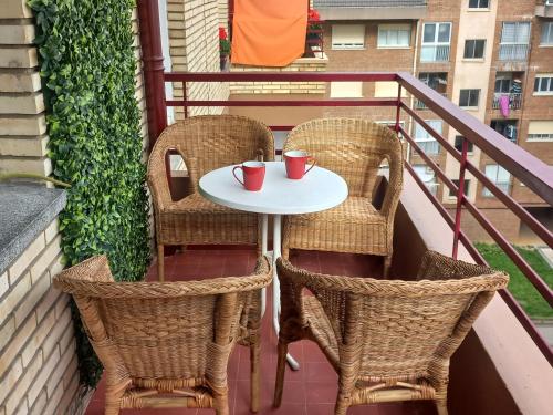a table and chairs on a balcony with two cups at Aroa's Home -Sirimiri Apartments- in Zumaia