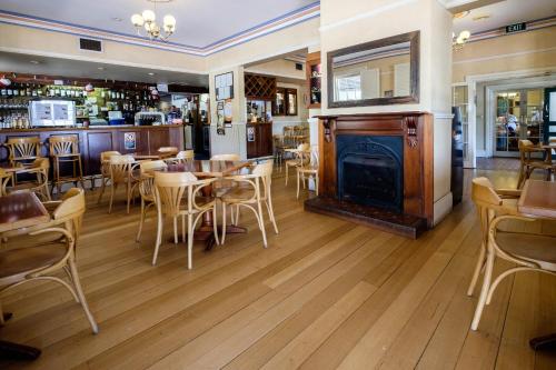 a restaurant with tables and chairs and a fireplace at Peel Inn Hotel Nundle in Nundle