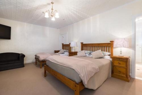 a bedroom with two beds and a couch and a tv at Peel Inn Hotel Nundle in Nundle