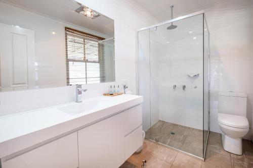 a white bathroom with a toilet and a shower at Peel Inn Hotel Nundle in Nundle
