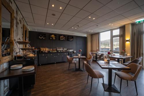 a restaurant with tables and chairs and a counter at Fletcher Hotel Restaurant Zeeduin in Wijk aan Zee
