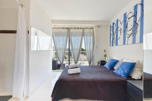 une chambre avec un grand lit avec des oreillers bleus dans l'établissement Cozy top-floor 2-Br apartment terrace and sea view, à Cannes