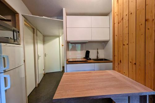 a small kitchen with white cabinets and a wooden floor at Au centre de la station 6 personnes in La Féclaz