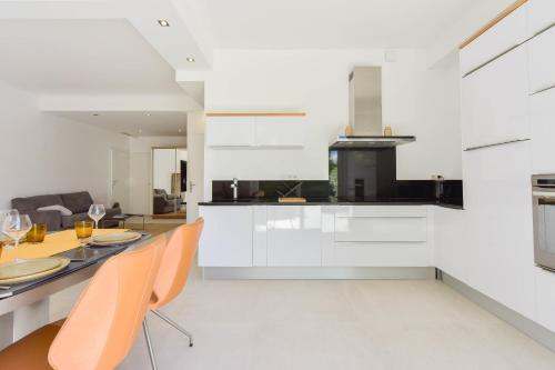 une cuisine avec des armoires blanches et une table et des chaises dans l'établissement First floor apartment walk to beach garage, à Cannes
