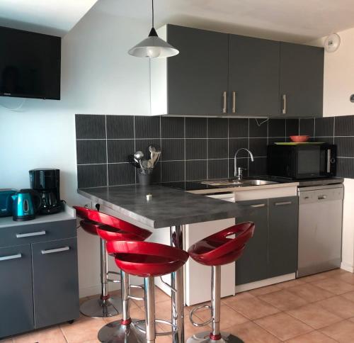 une cuisine avec des chaises rouges et un comptoir noir dans l'établissement Cozy cocoon just a stone's throw from the sea, au Pouliguen