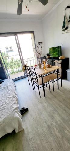 - une chambre avec une table, des chaises et une grande fenêtre dans l'établissement La Mouette 2 pièces rénovées et climatisé 300 plage et commerces, au Grau-du-Roi