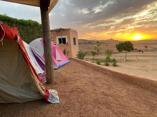 a tent in the desert with the sunset in the background at Les cavaliers chez Yassine in Marrakech
