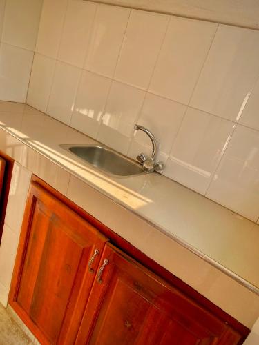a kitchen counter with a sink and white tiles at Safari Homes in Kampala
