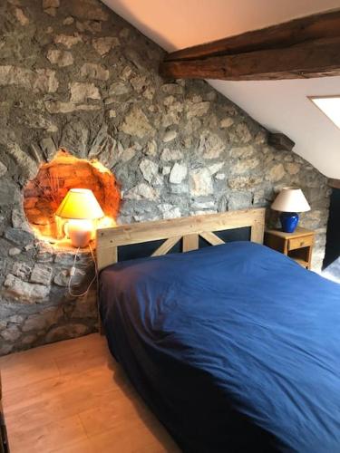 une chambre avec un lit et un mur en pierre dans l'établissement Villa piscine entre lac et montagne, à Grésy-sur-Aix