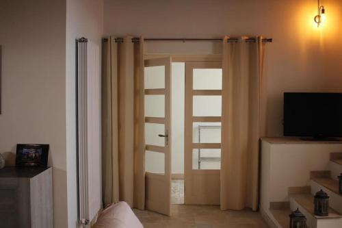 a room with a door with curtains and a television at Le relais in Prémeaux