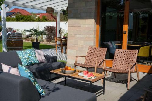a patio with two chairs and a table with fruit on it at ChaChaCha House Vendégház in Egerszalók