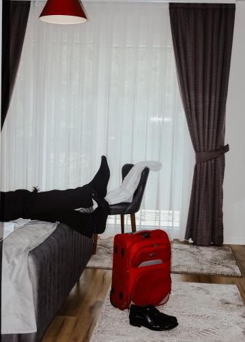 a person laying on a bed with a red suitcase at Andoena Resort in Lipjan
