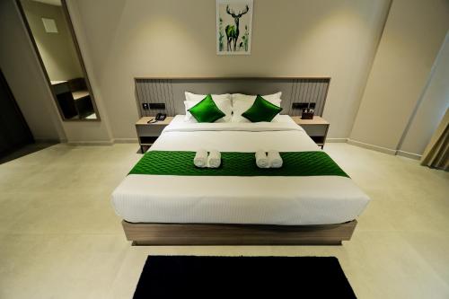a bedroom with a large bed with green pillows at Mount Land in Sultan Bathery