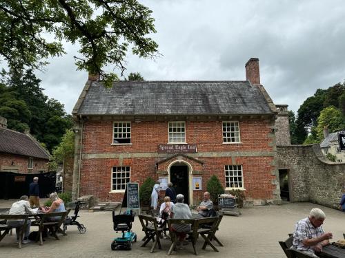 a group of people sitting at tables in front of a brick building at Spread Eagle Inn in Stourton