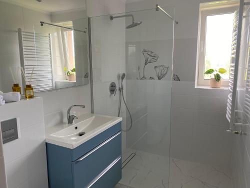a white bathroom with a sink and a shower at Apartamenty Uchnasta in Busko-Zdrój