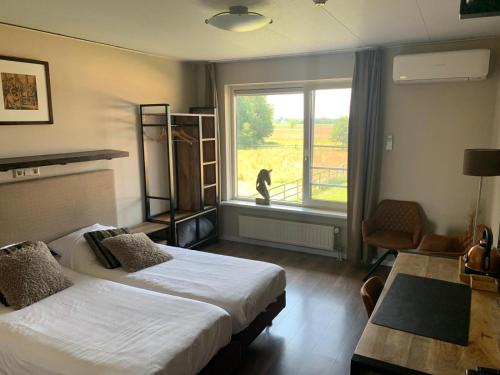 um quarto com duas camas e um gato a olhar pela janela em Human & Horse Hotel em Kootwijkerbroek