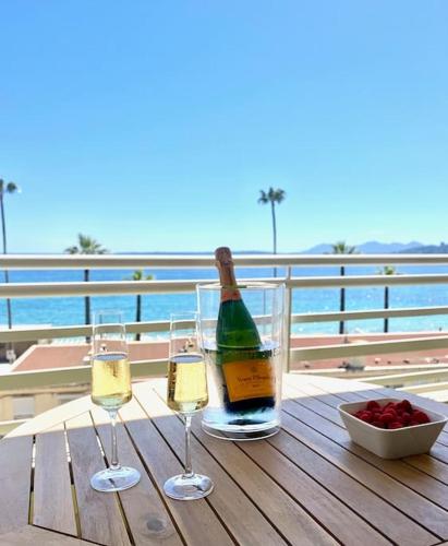 - une bouteille de vin et deux verres sur une table en bois dans l'établissement Magnifique T2 - Vue Mer - Parking - Juan-les-Pins, à Antibes