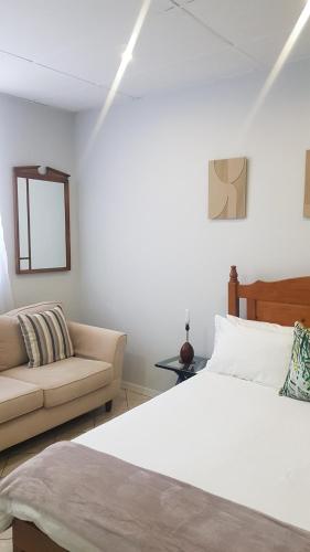 a white bedroom with a bed and a couch at Me Time in Johannesburg
