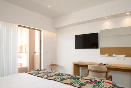 a hotel room with a bed and a desk and a television at High Beach Resort in Malia