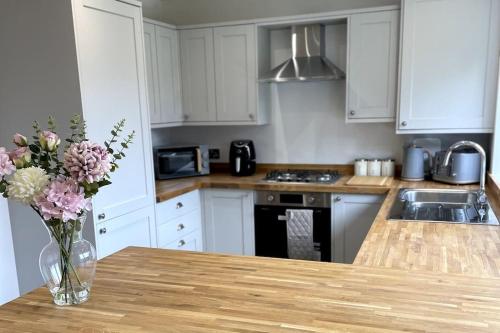 a kitchen with a vase of flowers on a table at Brand New Barn Conversion in Kings Bromley