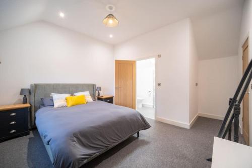 a bedroom with a bed with a yellow pillow at Brand New Barn Conversion in Kings Bromley