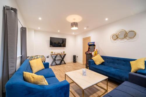 a living room with blue couches and a table at Brand New Barn Conversion in Kings Bromley