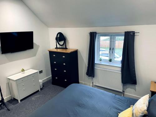 a bedroom with a bed and a dresser and a television at Brand New Barn Conversion in Kings Bromley