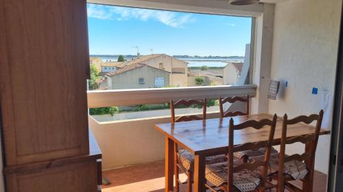 une salle à manger avec une table et une grande fenêtre dans l'établissement Studio 4 couchages - Floralies II - 700 m mer et centre, au Grau-du-Roi