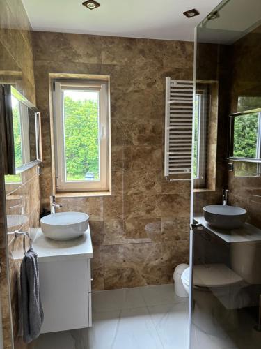 a bathroom with two sinks and a glass shower at Apartament nad Radunią in Kolbudy Dolne
